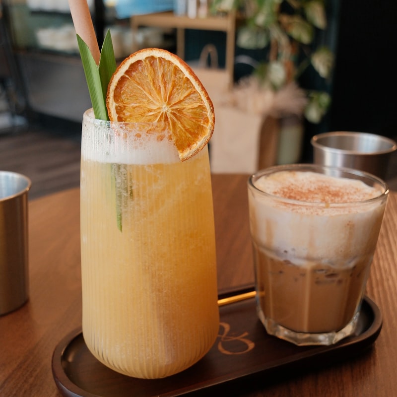 ドライオレンジを飾ったトロピカルドリンクとカフェラテ